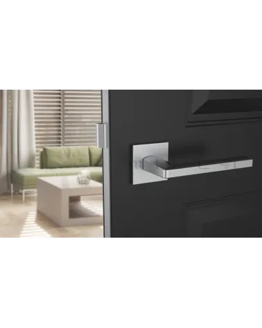 Poignée de porte chrome satiné PYROLA quincaillerie design vue de face montée sur une porte