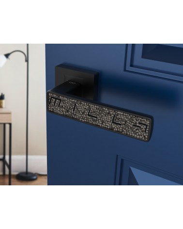 Poignée de porte noire GLAMOUR quincaillerie design vue inclinée montée sur une porte entrouverte