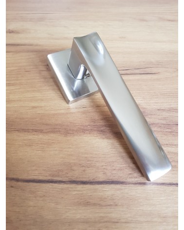 Poignée de porte nickel satiné DIUNA poignée design posée sur sol à motif bois