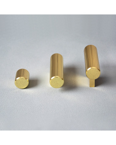 Bouton de meuble or poli AVANTI en T poignée design posé sur un fond gris