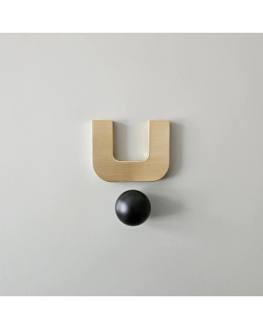 Poignée de meuble or poli ISA XS poignée design avec une sphère noire vue de face sur une surface claire