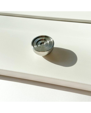 Bouton de meuble en acier inoxydable modèle 02 poignée design posé sur une surface éclairée projetant une ombre