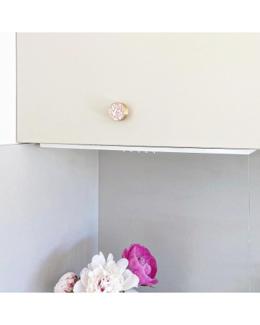 Bouton de meuble en laiton et Pink Terrazzo poignée design installée sur un meuble avec des fleurs roses en bas