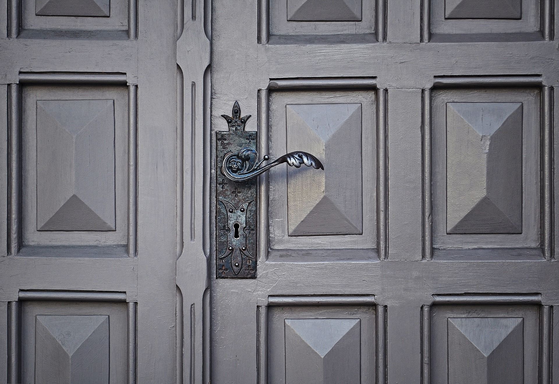 Black door handle fitted to a grey-coloured exterior door