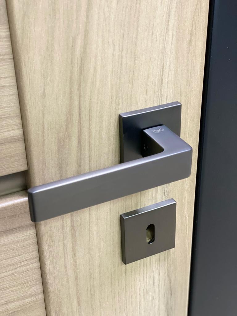 Design contemporary door handle on square plate in titanium/gun-metal colour