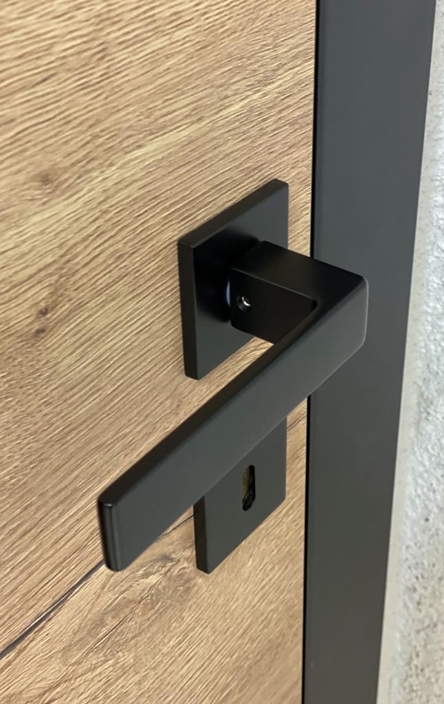 Contemporary black door handle from milla poignées with a rosette on a black square plate