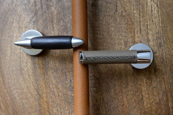 Swing door handles with a leather lever fitted on a dark wood door