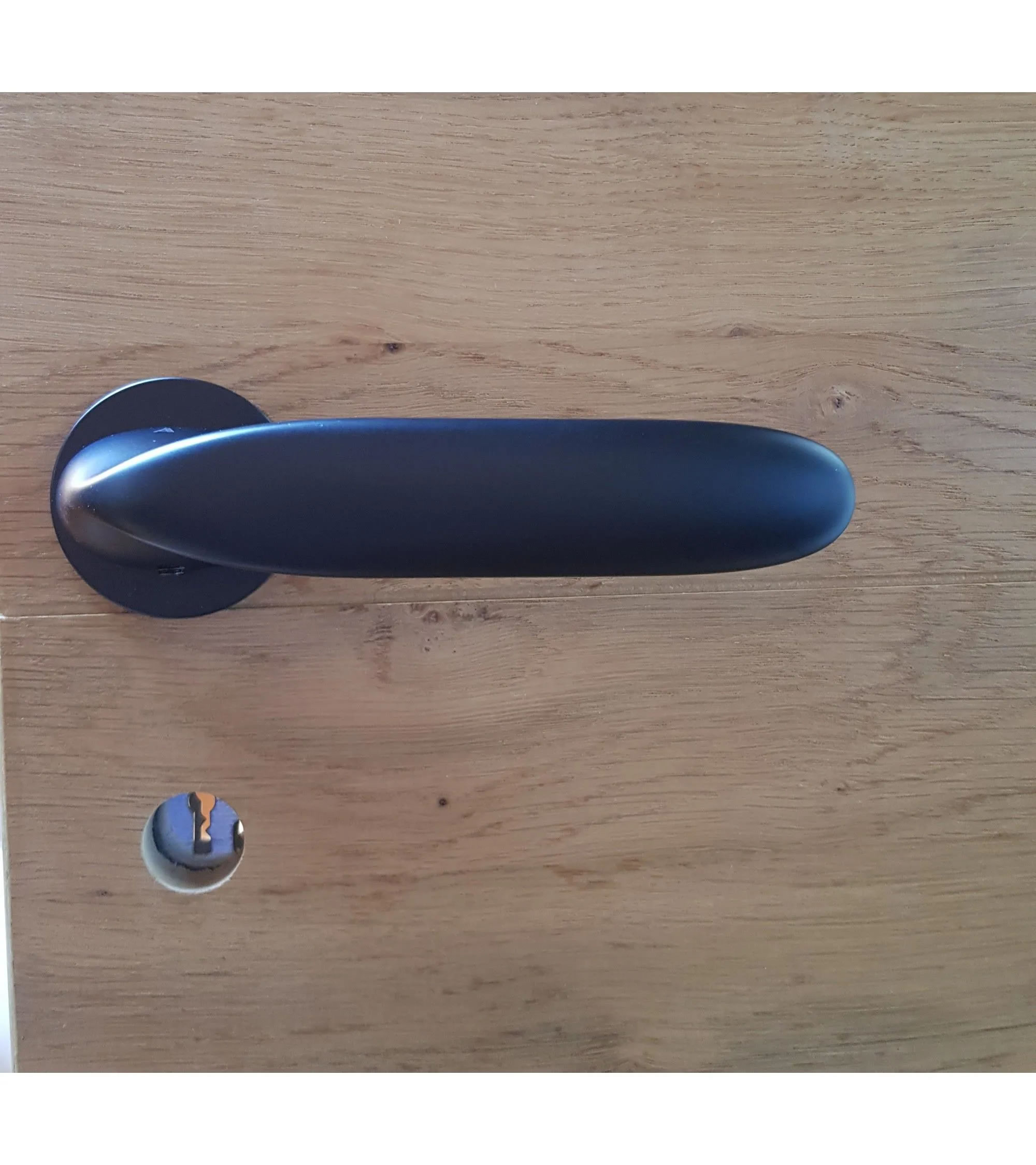 black door handle on a light wooden door sold by mille poignées
